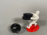 a small toy figurine of a man holding a tire and a wheel