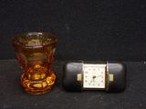 a small glass vase and a small clock on a table