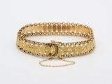 a close up of a gold bracelet on a white surface