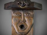 wooden carving of a man ' s face with a hat on top of his head