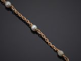 a gold chain bracelet with pearls on a black background