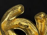 a gold snake that is sitting on a black surface