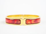 un gros plan d'un bracelet rouge et doré posé sur une surface blanche