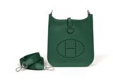 green leather handbag with keychain and strap on a white background