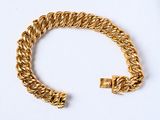 une image d'un bracelet en or sur une surface blanche