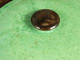 a green pot with a brown lid sitting on a table