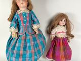 two dolls are standing next to each other on a white surface