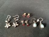 four pairs of earrings are sitting on a black surface