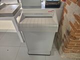 a white paper shredder sitting on the floor next to a brick wall