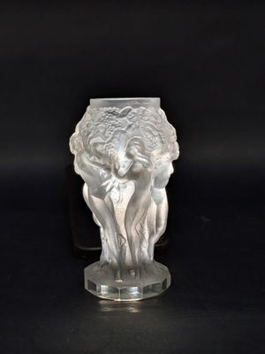 un vase en verre orné d'une statue, posé sur un fond noir