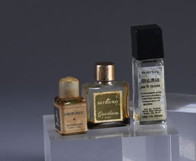 two bottles of perfume sitting on top of a clear shelf