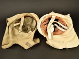 pair of old baseball helmets sitting on a black surface