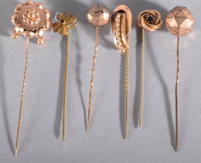 four gold hair pins are arranged in a row on a white surface