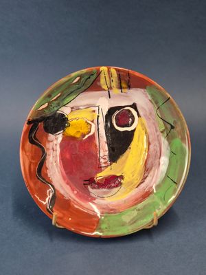 une assiette colorée ornée d'une peinture sur un fond bleu