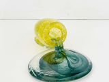 a glass vase with a yellow flower in it on a white surface