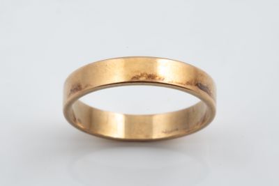 a close up of a gold wedding ring on a white background