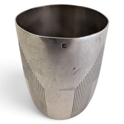 une tasse en métal posée sur une surface blanche