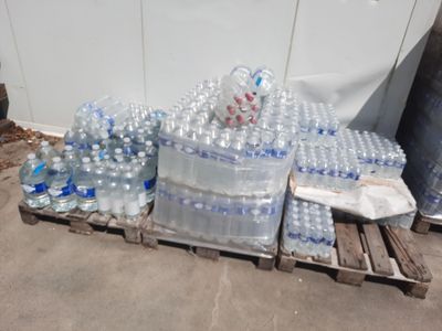 de nombreuses bouteilles d'eau posées sur une palette près d'un mur