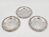 trois sous-verres en métal argenté sur fond blanc