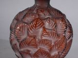 a brown vase with leaves on it on a white surface