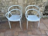 two white chairs sitting next to each other on a brick floor