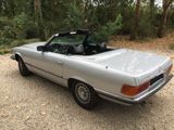 an image of a silver convertible car parked on a gravel road