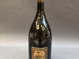 a bottle of wine sitting on top of a table next to a gray background