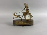 une horloge en or sur laquelle figurent une dame et un chien