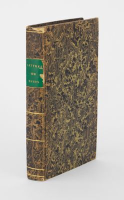 un livre à la couverture verte posé sur une surface blanche