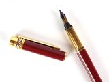 un gros plan d'un stylo plume avec une plume rouge et une plume dorée