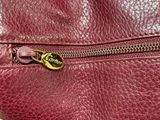 the zipper of a red leather purse with a gold metal clasp