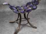 une image représentant un bol en verre violet posé sur un socle en métal