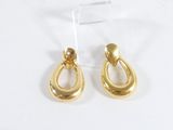 boucles d'oreilles en forme de larme plaquées or, présentées sur un support en acrylique transparent