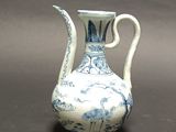 a blue and white vase with a handle on a table