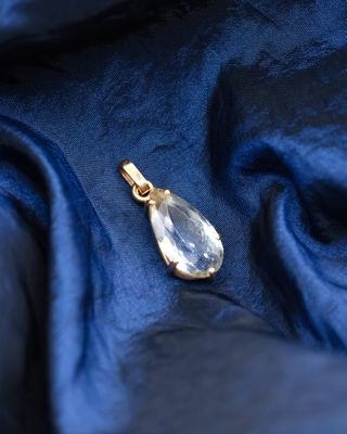 a close up of a gold pendant on a blue fabric