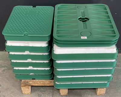 plusieurs bacs en plastique verts empilés les uns sur les autres sur une palette