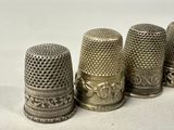 three antique thimbles are lined up on a white surface