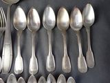 a lot of silver spoons and forks laid out on a table