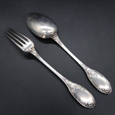 two silver spoons and a fork on a black surface