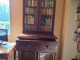 a desk with a computer and a bookcase in the corner