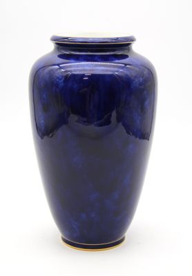 un vase bleu posé sur une surface blanche