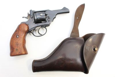 un vieux revolver et un étui en cuir posés sur une surface blanche