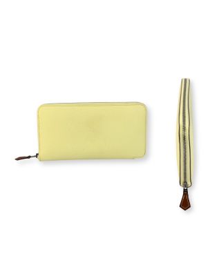 le portefeuille en cuir jaune se trouve à côté d'un stylo en cuir marron