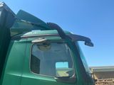 a green truck parked in a lot with a blue sky in the background