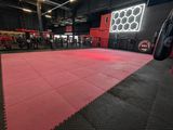 an empty gym with a red floor and a punching bag