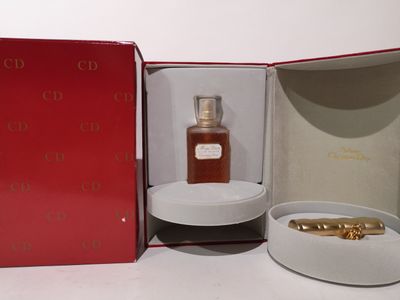 une boîte rouge contenant un flacon de parfum et une bague en or