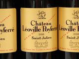 three bottles of red wine are lined up on a shelf