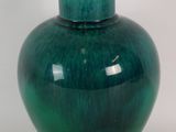 a green vase that is sitting on a white surface