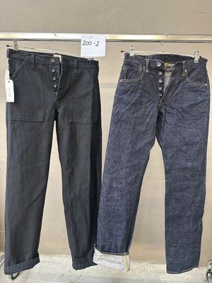trois paires de jeans suspendues à un portant dans un magasin