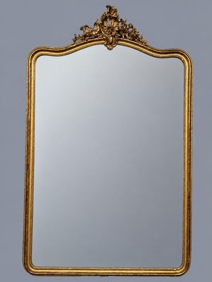 a gold framed mirror on a wall with a gray background